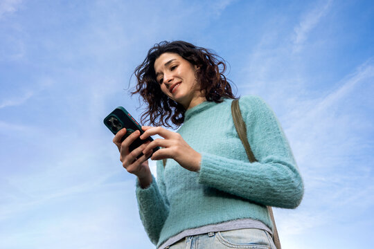 Woman Using Smartphone Under Blue Sky Enjoying the Day