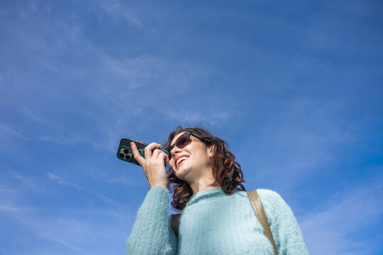 Smiling Woman on a Sunny Day Speaking With Phone Outdoors