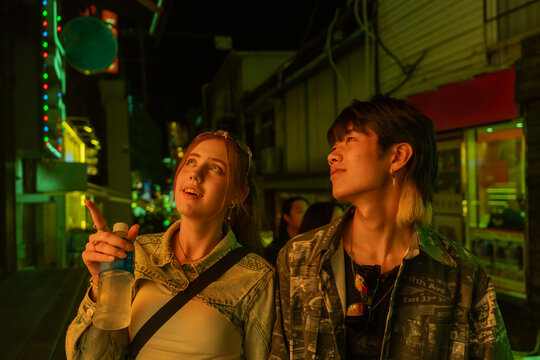 Young Couple Enjoying a Vibrant Night in a Colorful Street Market