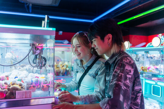 Young Couple Enjoys Claw Machine Fun at Arcade in Bright Lighting
