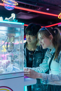 Friends Enjoy Time at Arcade While Playing Claw Machine in Evening