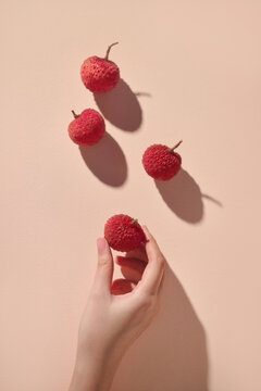A hand holding a single lychee with others