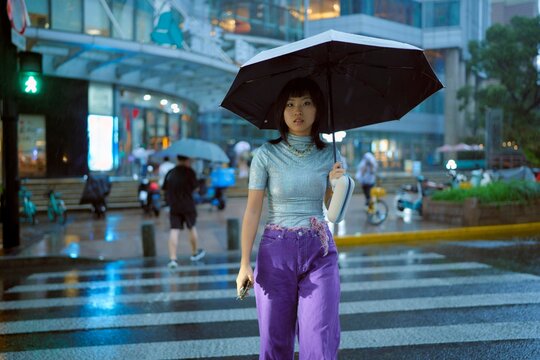 Young Woman Holding Umbrella on Busy City Street During Rain