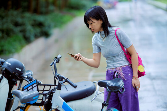 Young Woman Checking Her Phone Near Bicycles on a Quiet Street