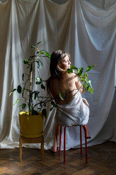 A woman sits near a flower in a pot