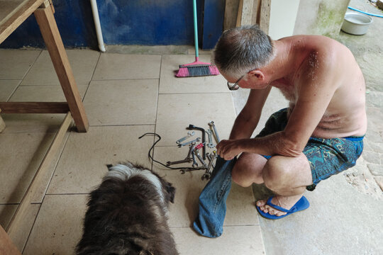 Senior male arranging his tools in the garage with his dog