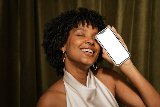 Woman with a smartphone with white screen smiles in studio