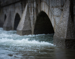 Floodwater overtopping a retaining wall with partially submerged culverts