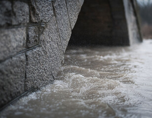 Floodwater overtopping a retaining wall with partially submerged culverts