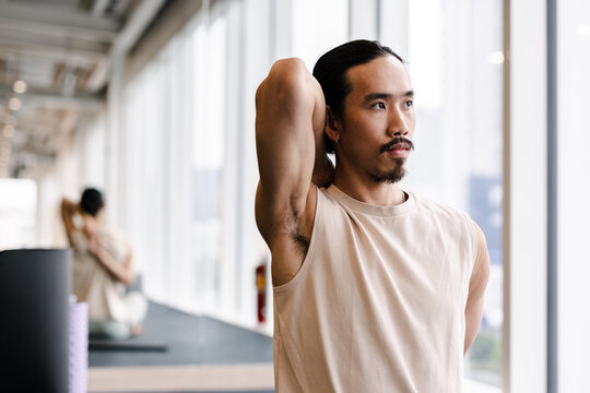 Asian Man Posing with Arm Behind Head in Bright Studio
