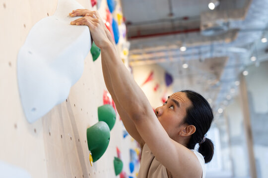 Climber Reaches for a Big White Hold in Indoor Bouldering Gym 