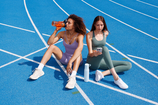 Two Athletes women rest on track after outdoor workout