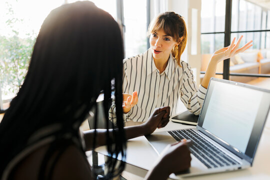 Businesswomen discussing strategy using laptop in office
