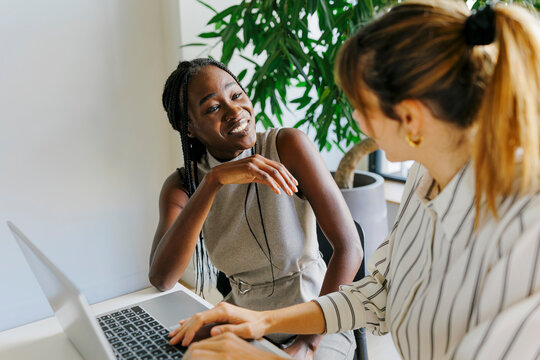 Businesswomen collaborating on laptop in modern office