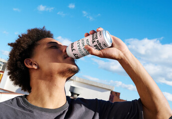 Real photo of Man Drinks From a Can on a Rooftop. PSD mockup