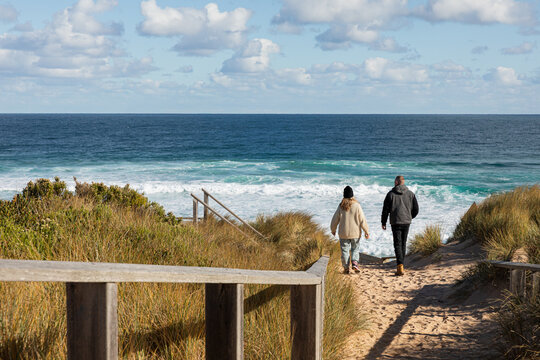 Couple walking together on a sandy beach path in Phillip Island