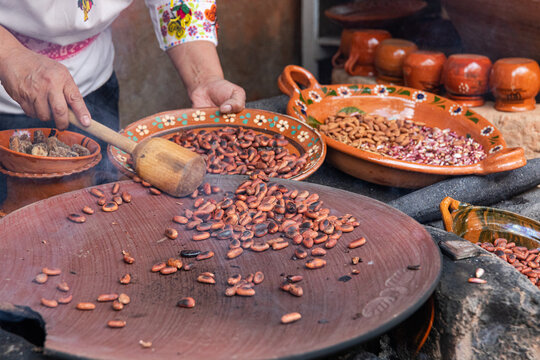 Roasting cacao beans over a comal in a traditional Mexican kitchen
