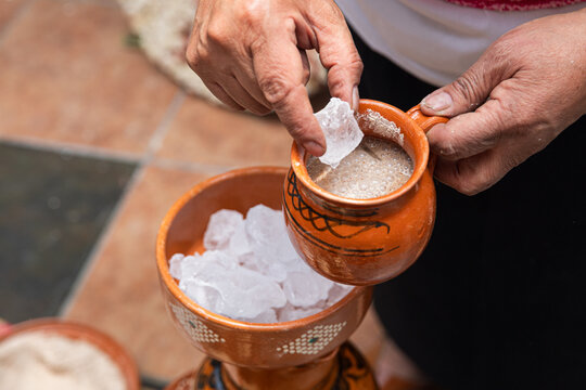 Hand pouring beverage with ice into clay mug