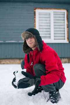 A young man plays in the snow near the house