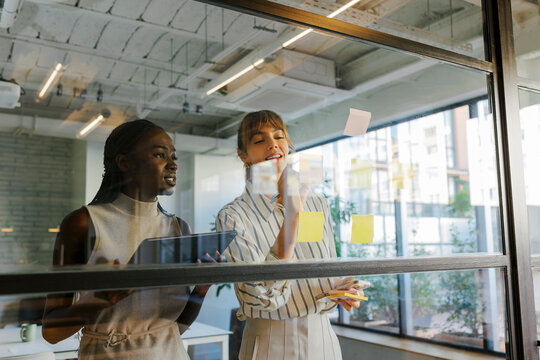 Businesswomen brainstorming ideas on glass wall