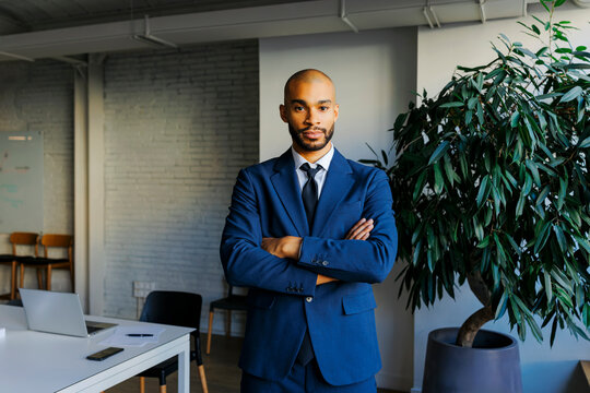 Professional businessman standing with arms crossed in office