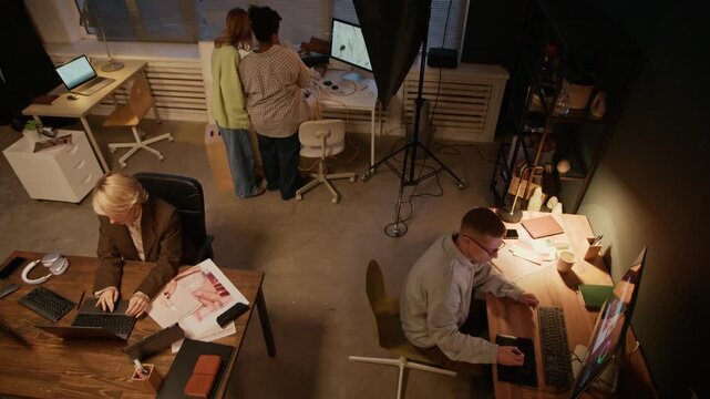 High angle shot of biracial team including photographer, designer, producer and retoucher working in modern studio together