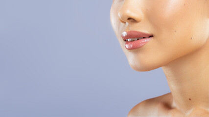 Fototapeta premium A woman poses for a close-up shot showing her face. The focus is on her smooth skin and natural glow. The background is a simple, muted color enhancing her features.