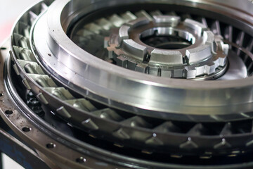 Close up high angle of a shiny metallic turbine engine component with intricate mechanical details and precision engineering parts in a workshop. © Jumain