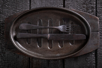 Black empty metal grill plate on burnt table.