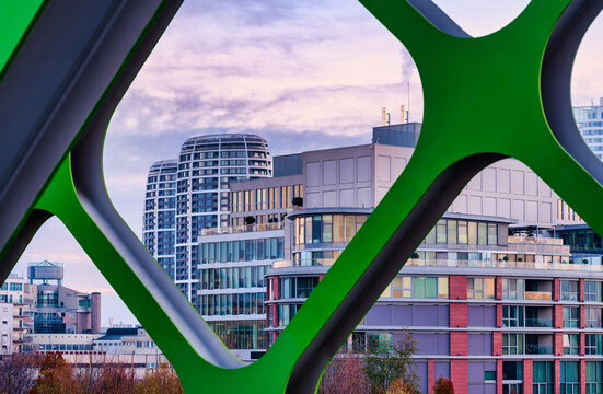 Modern District Buildings Framed By Green Old Bridge Truss At Dawn