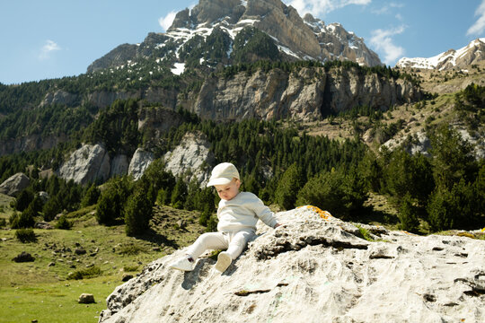 Joyful child sliding on a rock in a vibrant mountain setting