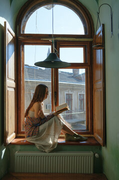 a woman with a book by the window