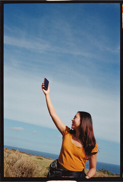Woman holding phone against sky looking for cell service 