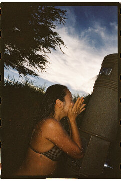 Woman washing face in outdoor shower at the beach