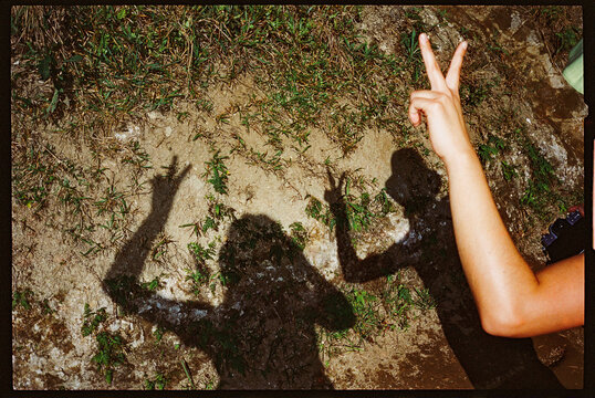 Shadow of two women holding up peace signs on a trail