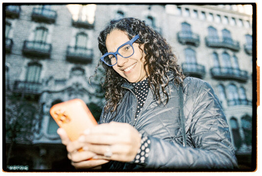 Smiling Woman Using Smartphone Outdoors in Urban Setting