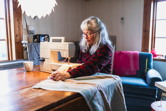 Senior Woman Sewing with Machine in Cozy Home