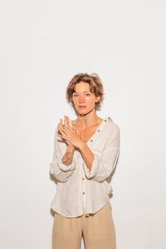Woman standing against plain background with hands together