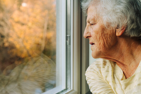 Senior woman looking outside window