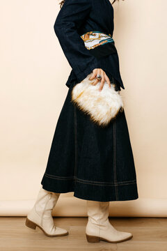 Woman with denim skirt holding faux fur clutch