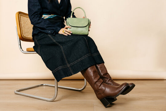 Anonymous woman sitting with green handbag