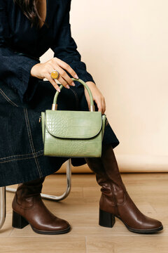 Woman holding contemporary green fashion handbag and wearing boots