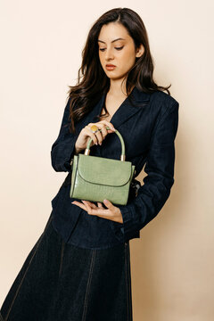 Woman holding green crocodile-effect fashion handbag