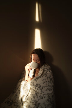 Cozy morning scene with a woman wrapped in a blanket