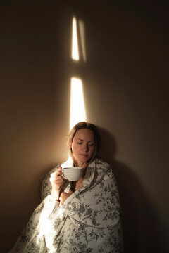 Cozy morning scene with a woman wrapped in a blanket