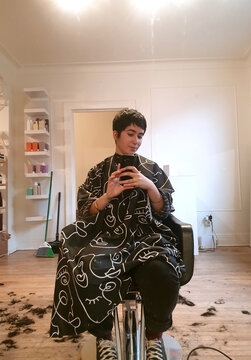 Androgynous young woman at the hairdresser with short pixie haircut.