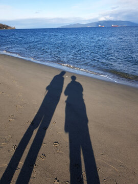 Extended shadows of a couple on the sea shore