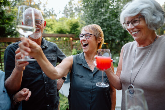 Candid garden party with friends toasting wine and juice, joyful