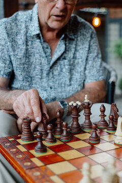 Candid moment of an elderly man focused on a chess game at a tab