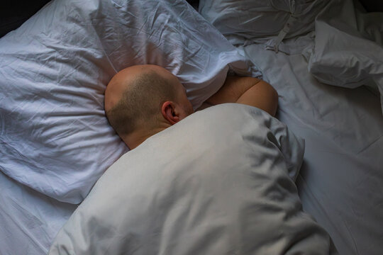 Man Resting in Bed Under White Sheets During Morning Light